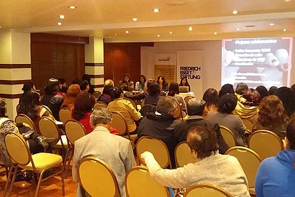 Los participantes escuchan a las ponentes en una sala de eventos.
